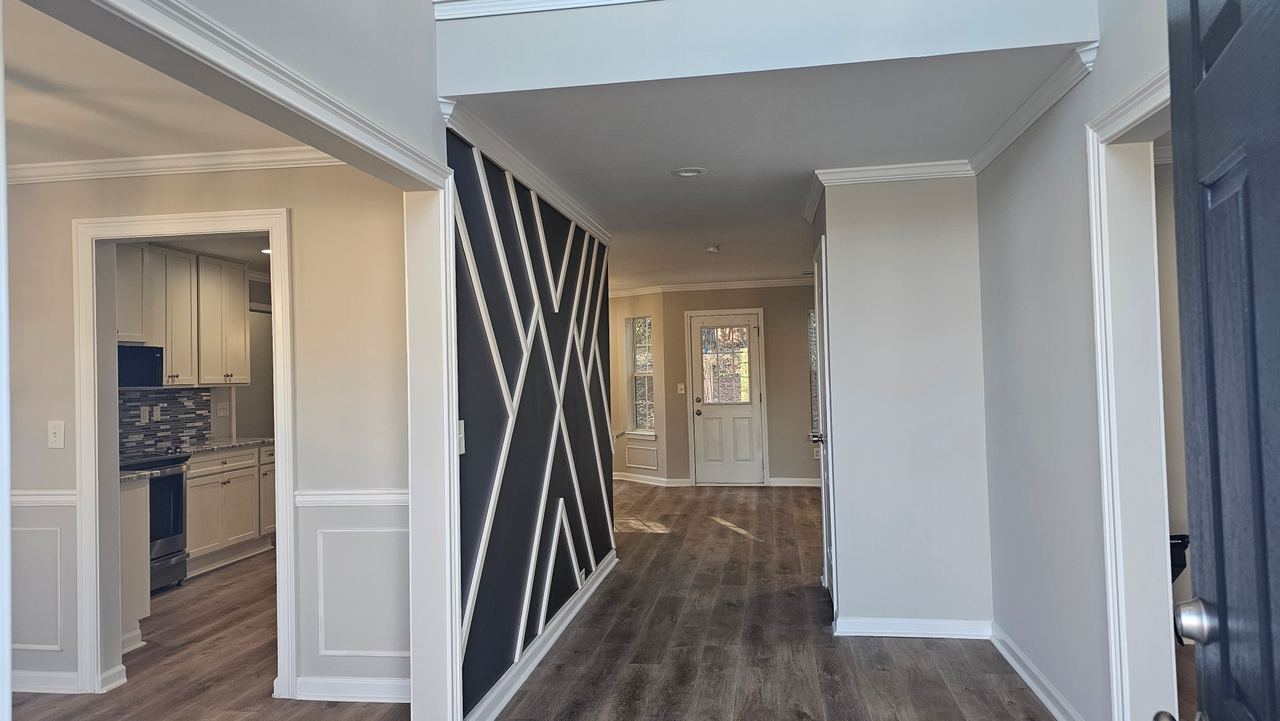 The completed entry hall, its geometric accent wall facing the front door, with the kitchen through the left-hand opening.