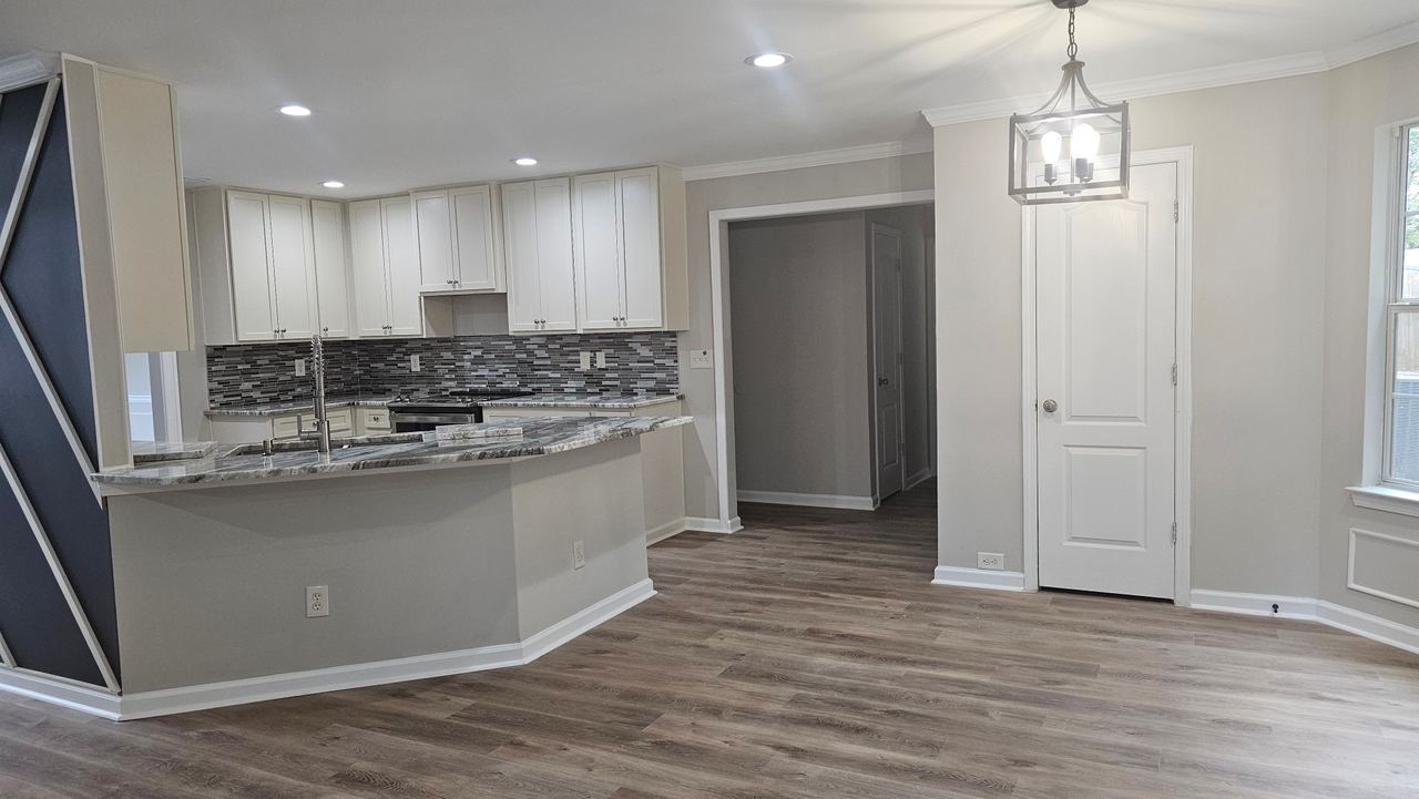 A wider view of the finished kitchen and the adjoining dining area, with a lantern pendant and the front door beyond.
