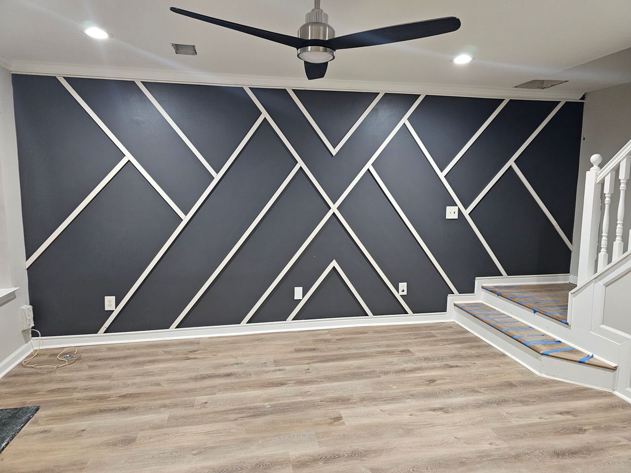 The same grey wall finished, with white battens forming a geometric pattern, beside a staircase.